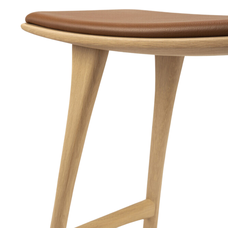 The Upholstered Osso Counter Stool from Ethnicraft with oak wood and cognac leather close up.