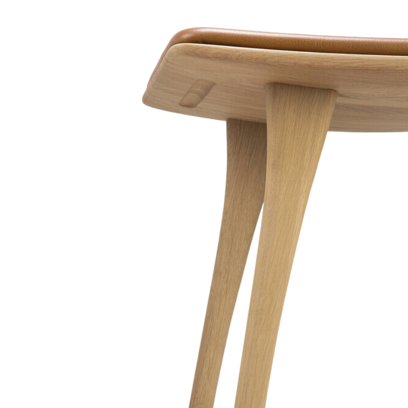 The Upholstered Osso Counter Stool from Ethnicraft with oak wood and cognac leather in detail.