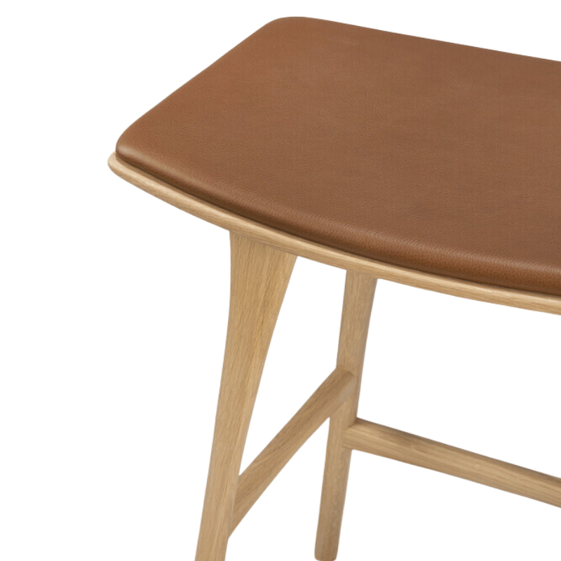 The Upholstered Osso Counter Stool from Ethnicraft with oak wood and cognac leather seat.