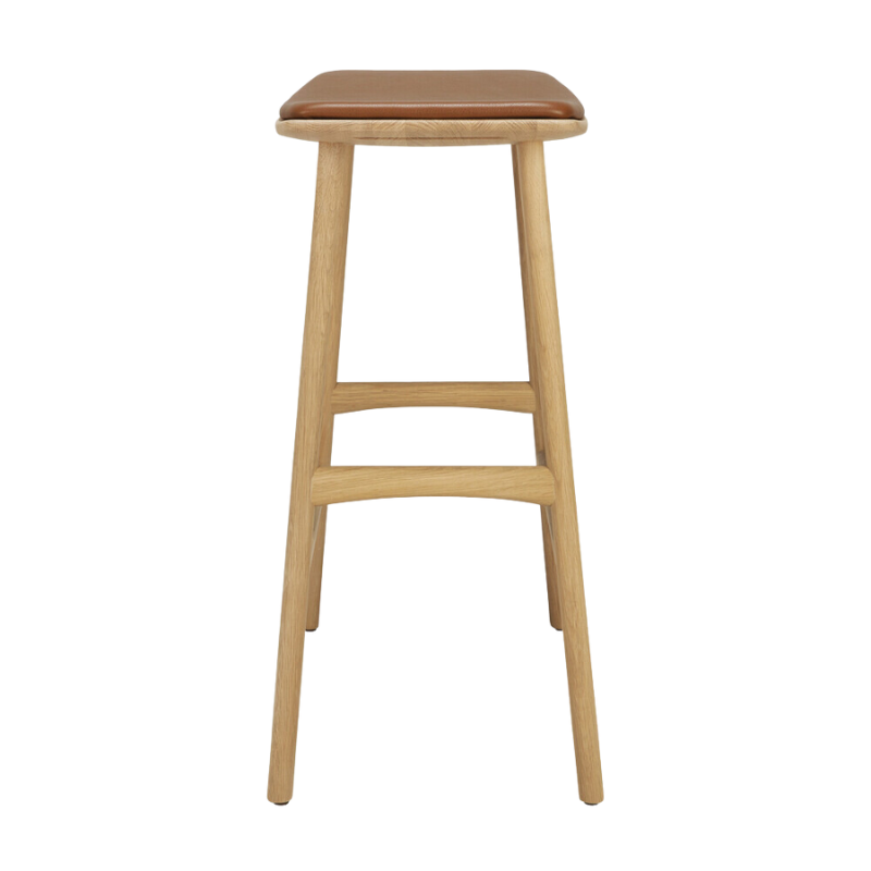 The Upholstered Osso Counter Stool from Ethnicraft with oak wood and cognac leather from the side.
