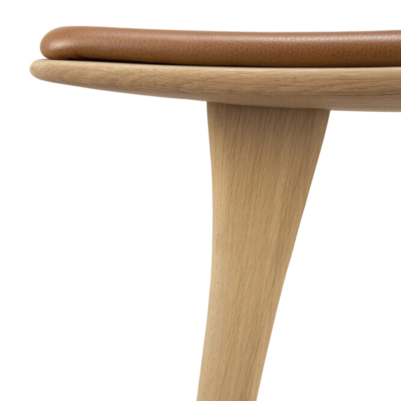 The Upholstered Osso Counter Stool from Ethnicraft with oak wood and cognac leather upholstery.
