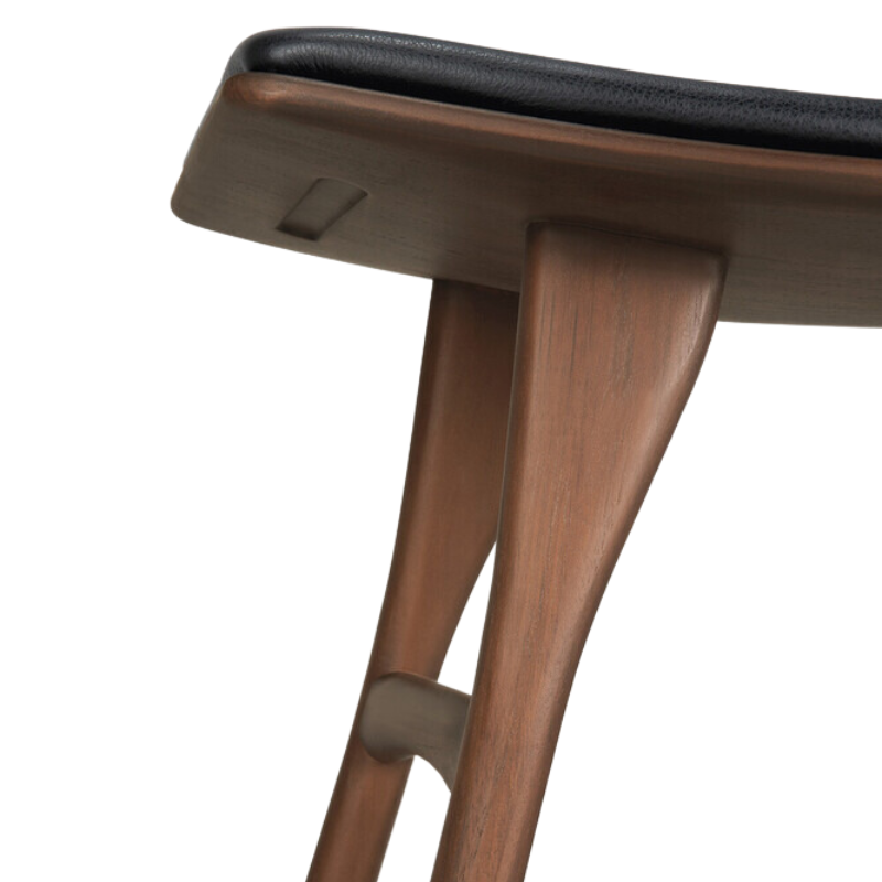The Upholstered Osso Dining Stool from Ethnicraft with brown teak and black leather in detail.