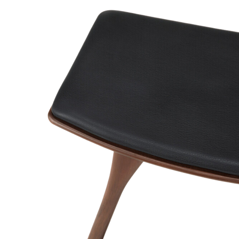 The Upholstered Osso Dining Stool from Ethnicraft with brown teak and black leather seat.