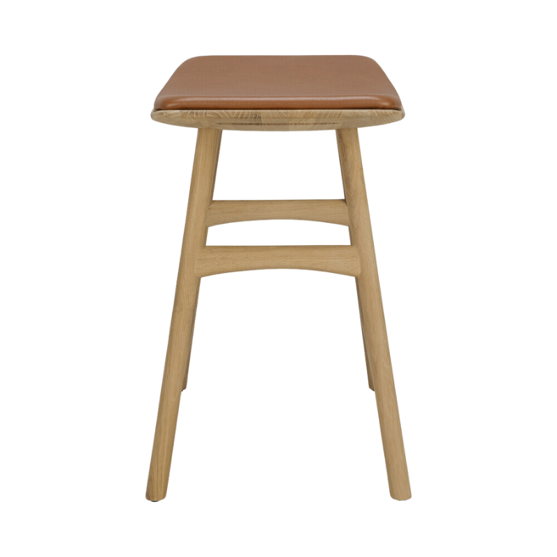 The Upholstered Osso Dining Stool from Ethnicraft with oak and cognac leather from the side.