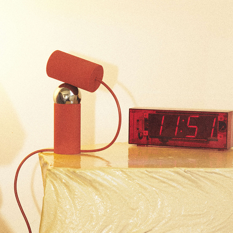 The Bilboquet Table Lamp from FLOS in tomato in a bedroom.