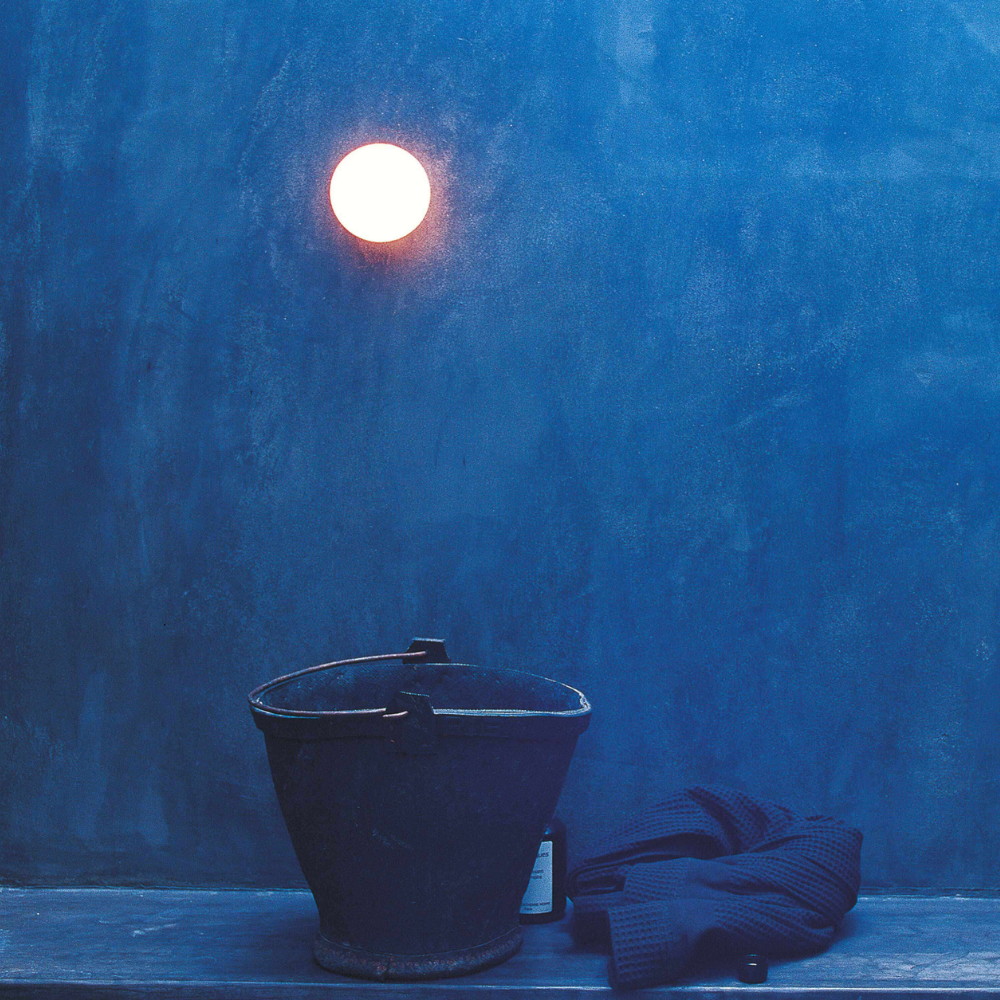 The Glo-Ball Mini Ceiling/Wall Light from Flos on a blue wall.