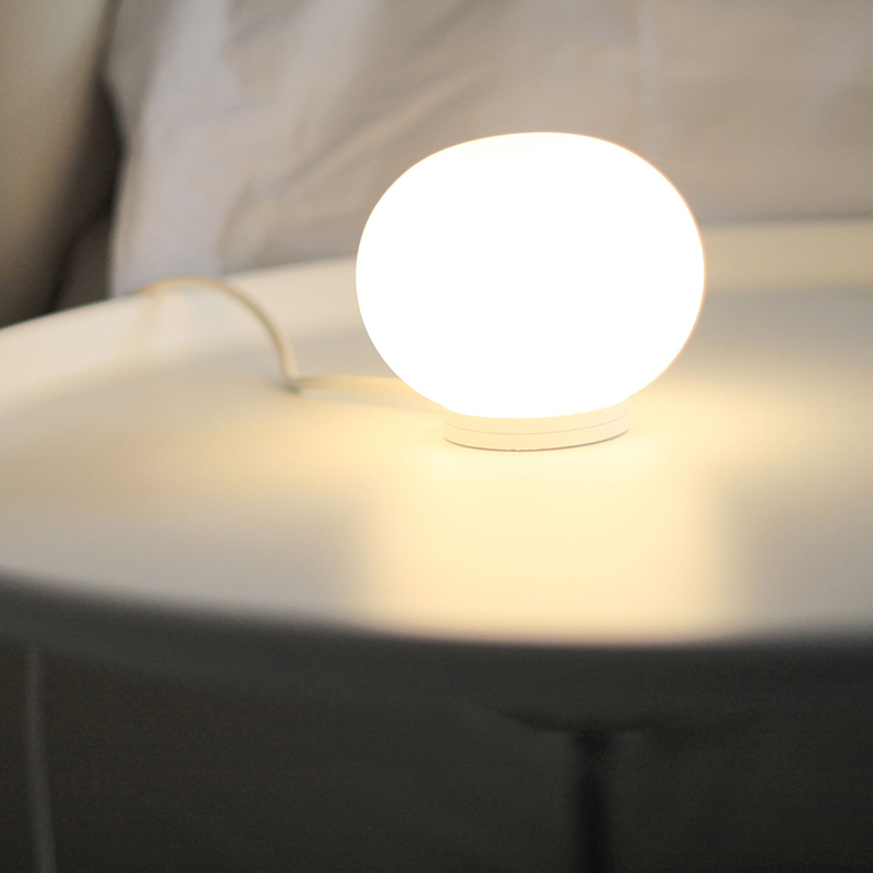 The Mini Glo-Ball Table Lamp from Flos in a workspace.