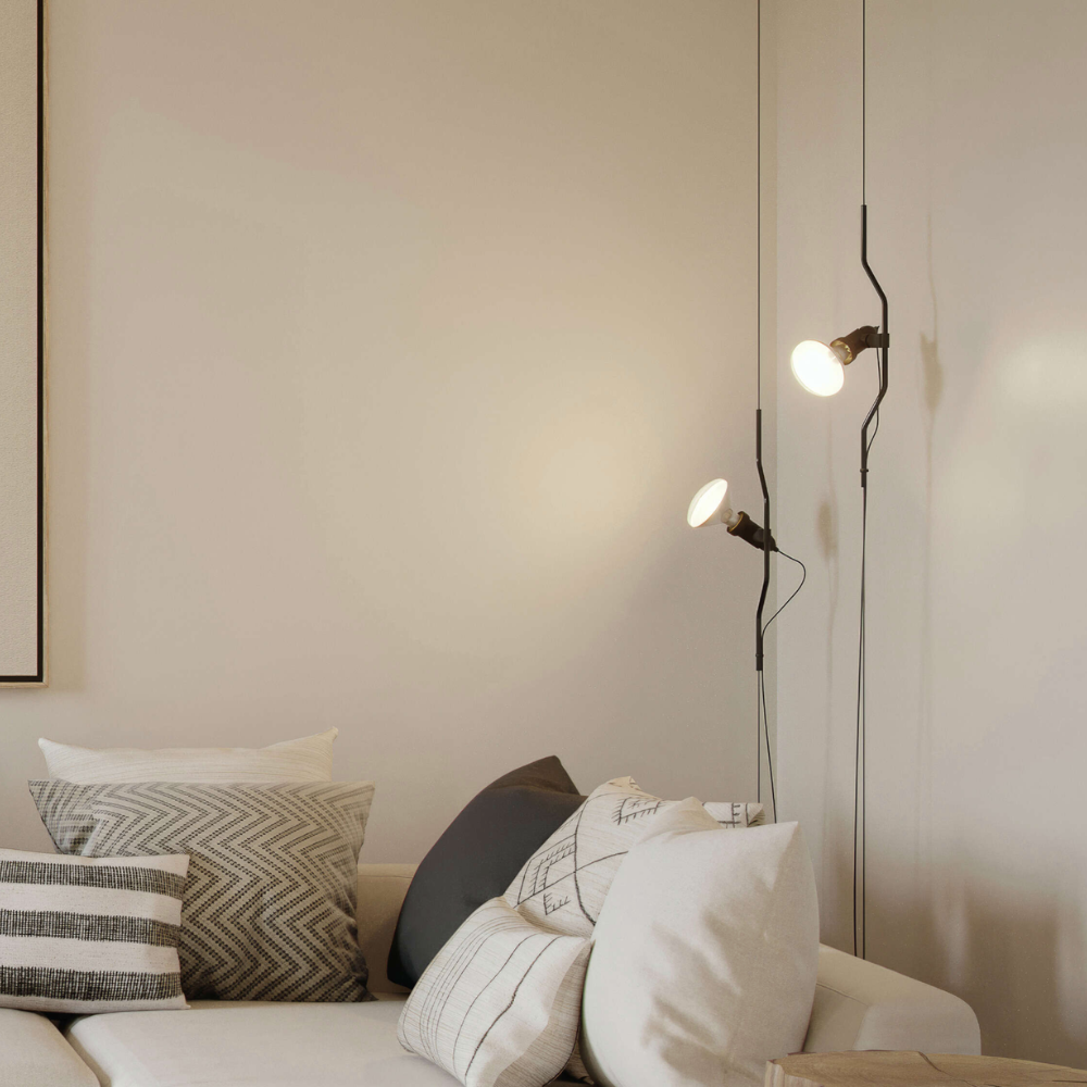 The Parentesi Lamp from Flos in Black next to a sofa in a living room.