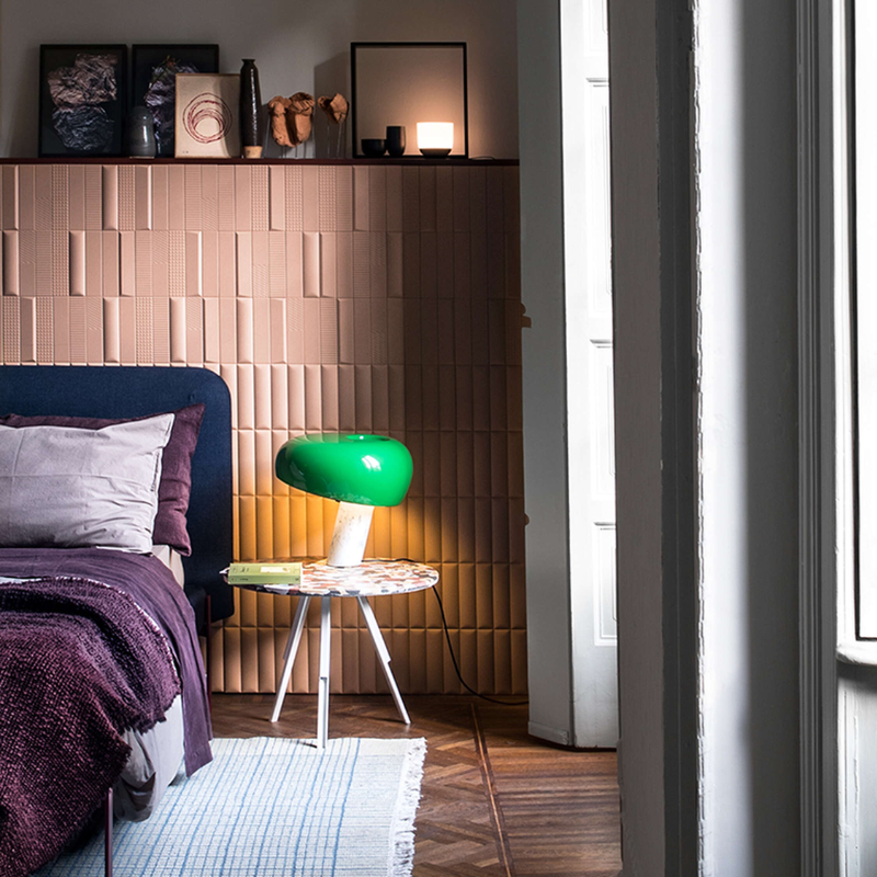 The Snoopy Table Lamp from FLOS in green on a bedside table.