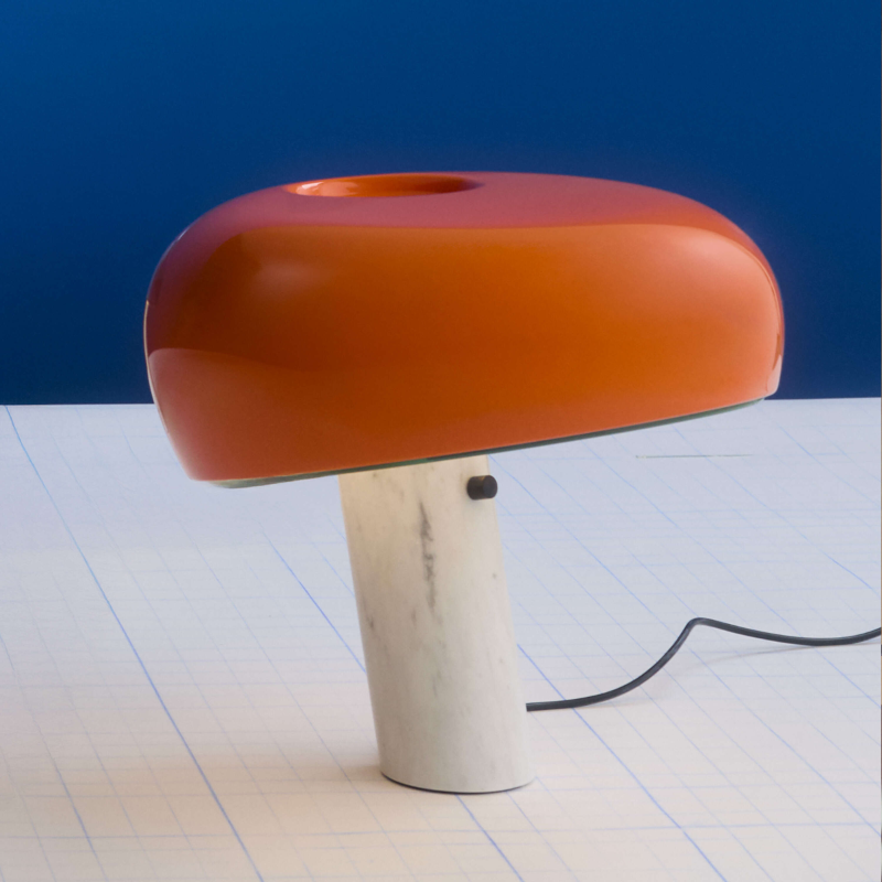 The Snoopy Table Lamp from FLOS in orange in an art studio.