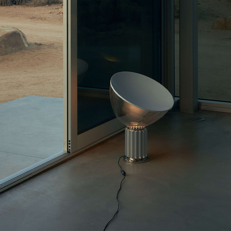 The standard Taccia Table Lamp from FLOS in silver next to a doorway.