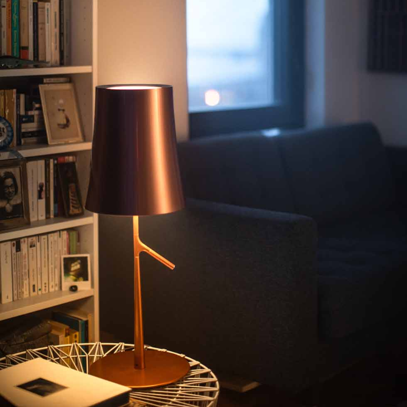 The Birdie Table Lamp from Foscarini in copper in a living room.