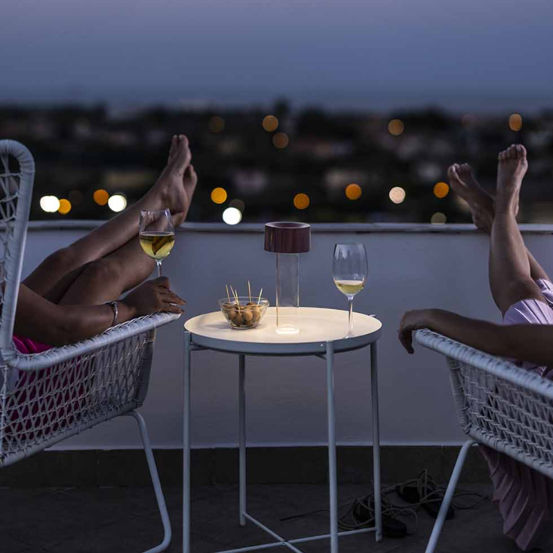 The Fleur Portable Lamp from Foscarini in burgundy outdoors.