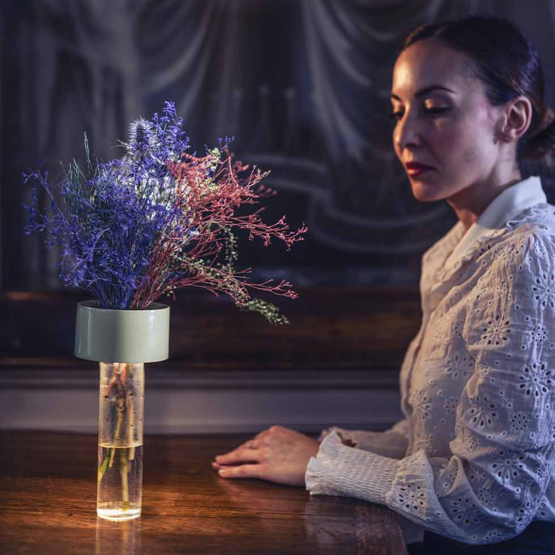 The Fleur Portable Lamp from Foscarini in sage green in a dining room.