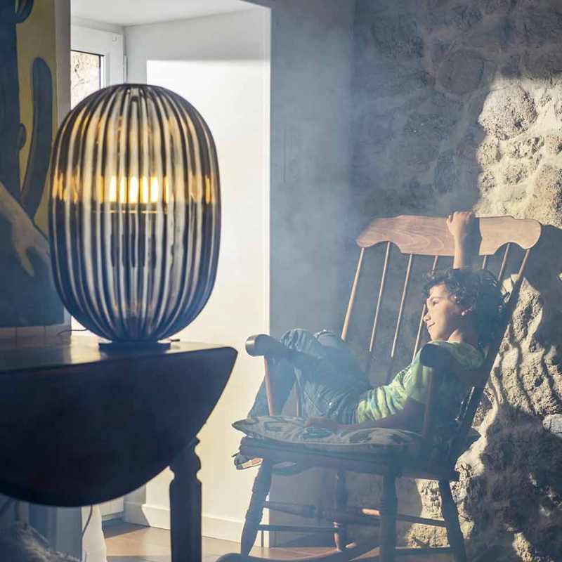 The Plass Table Lamp from Foscarini in grey in a living room.