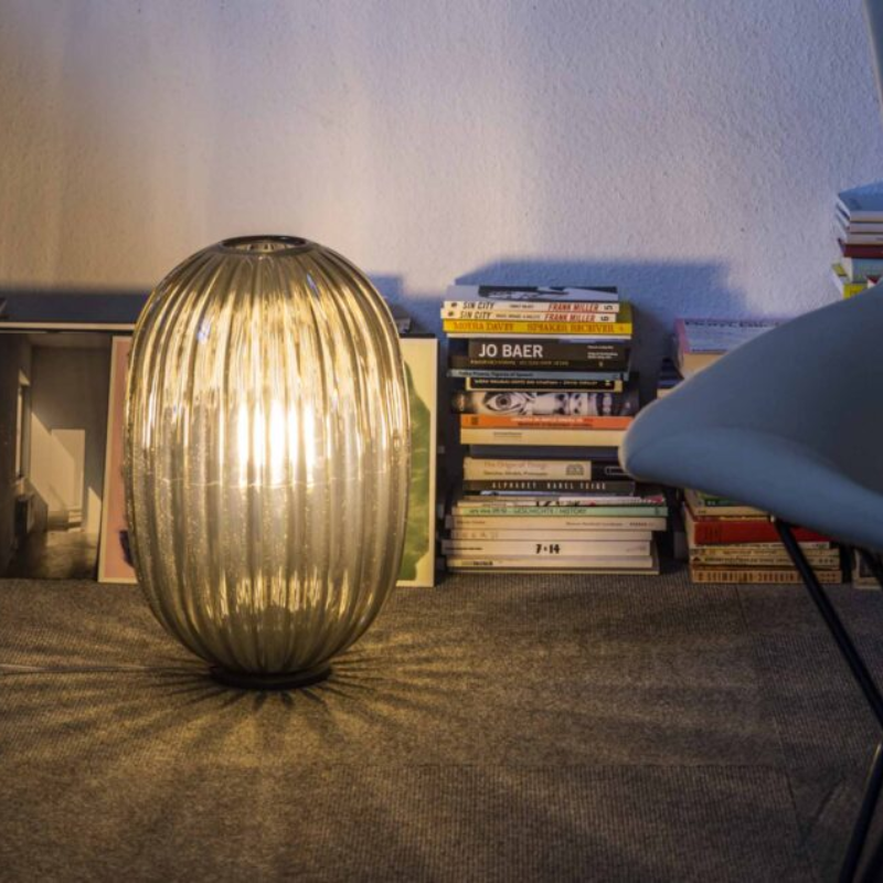 The Plass Table Lamp from Foscarini in grey in a lounge.