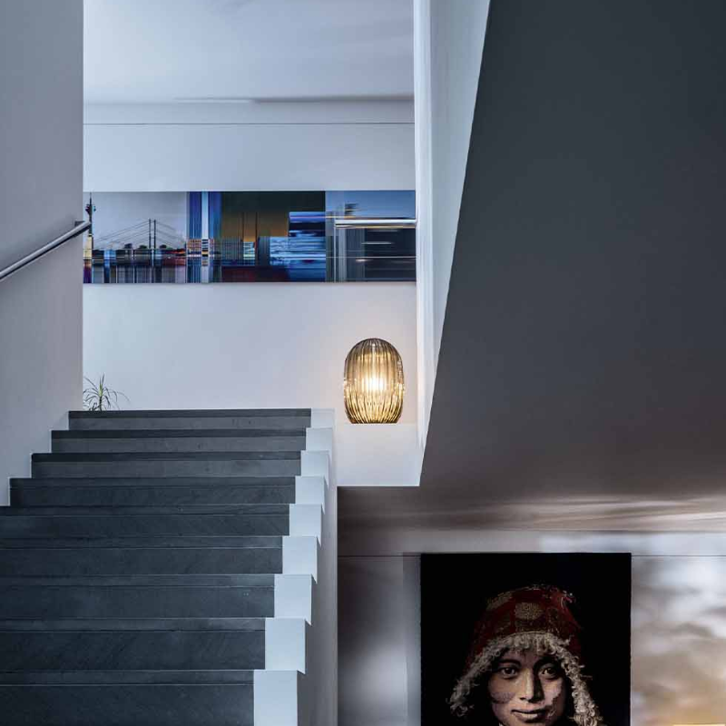 The Plass Table Lamp from Foscarini in grey near a staircase.