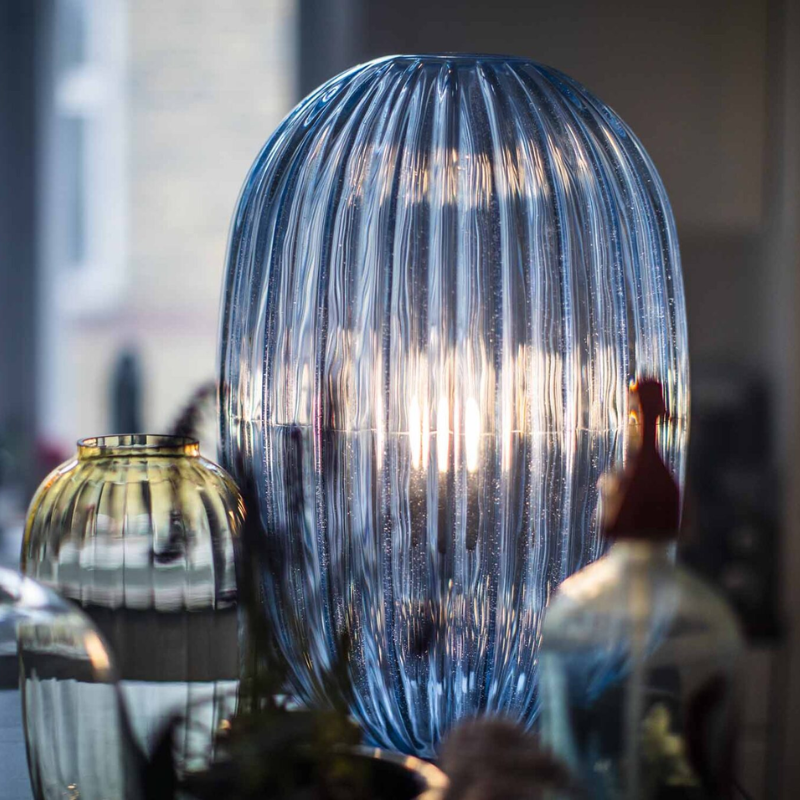 The Plass Table Lamp from Foscarini in light blue in a dining room.
