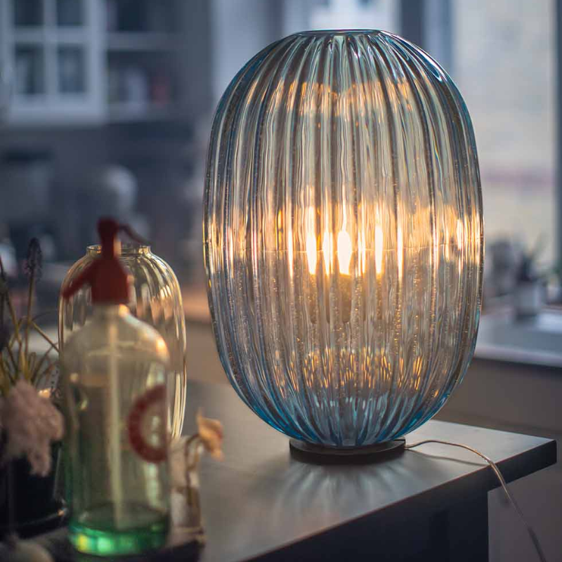 The Plass Table Lamp from Foscarini in light blue in a living space.