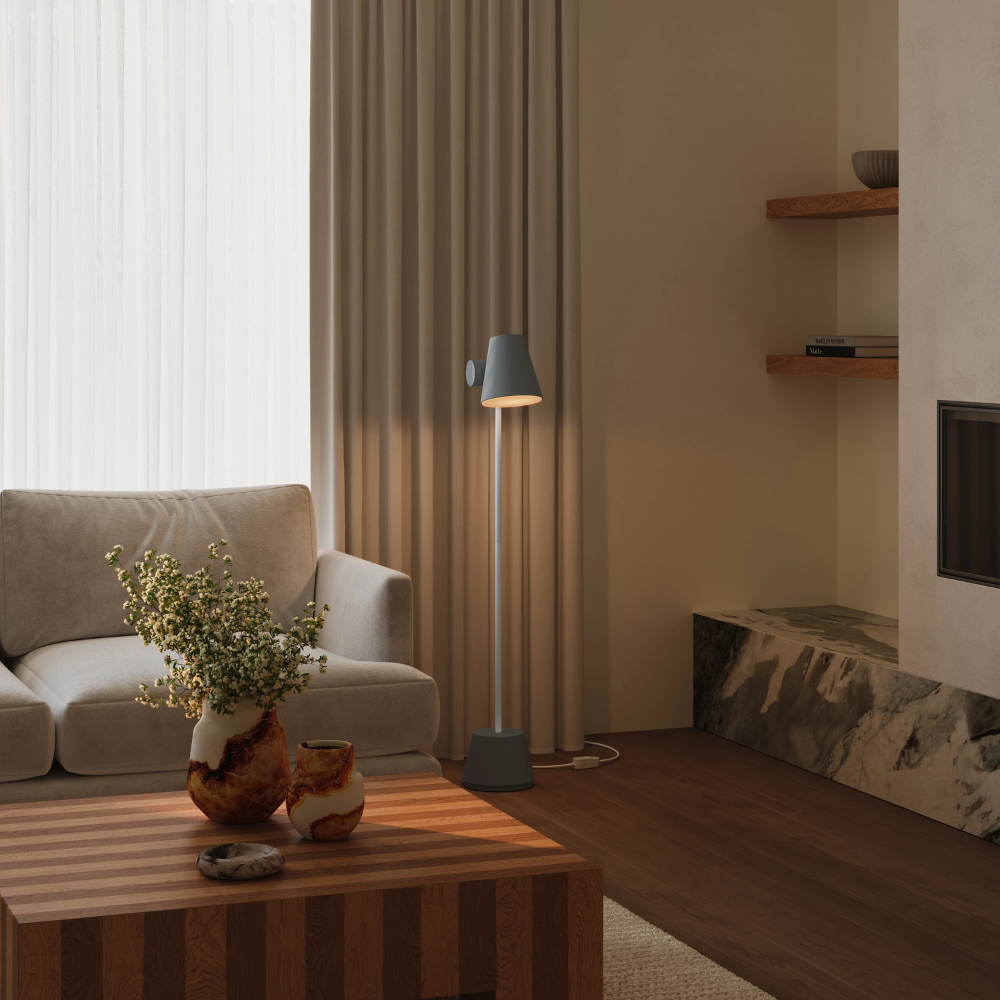 The fog Aim Floor Light from Gantri with the white rod option in a living room next to a couch.