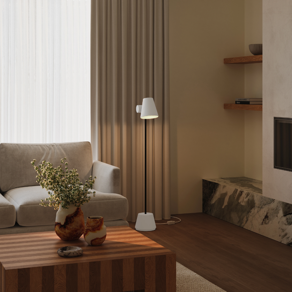 The stone Aim Floor Light from Gantri with the black rod option in a family area next to a sofa and fireplace.