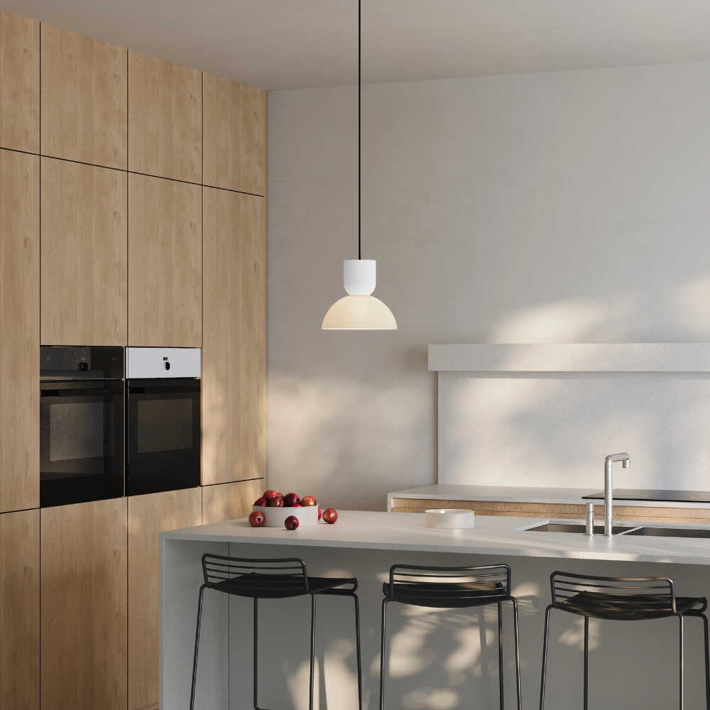 The snow Buia Pendant Light from Gantri with the black cord in a dining and kitchen area above a kitchen bar.