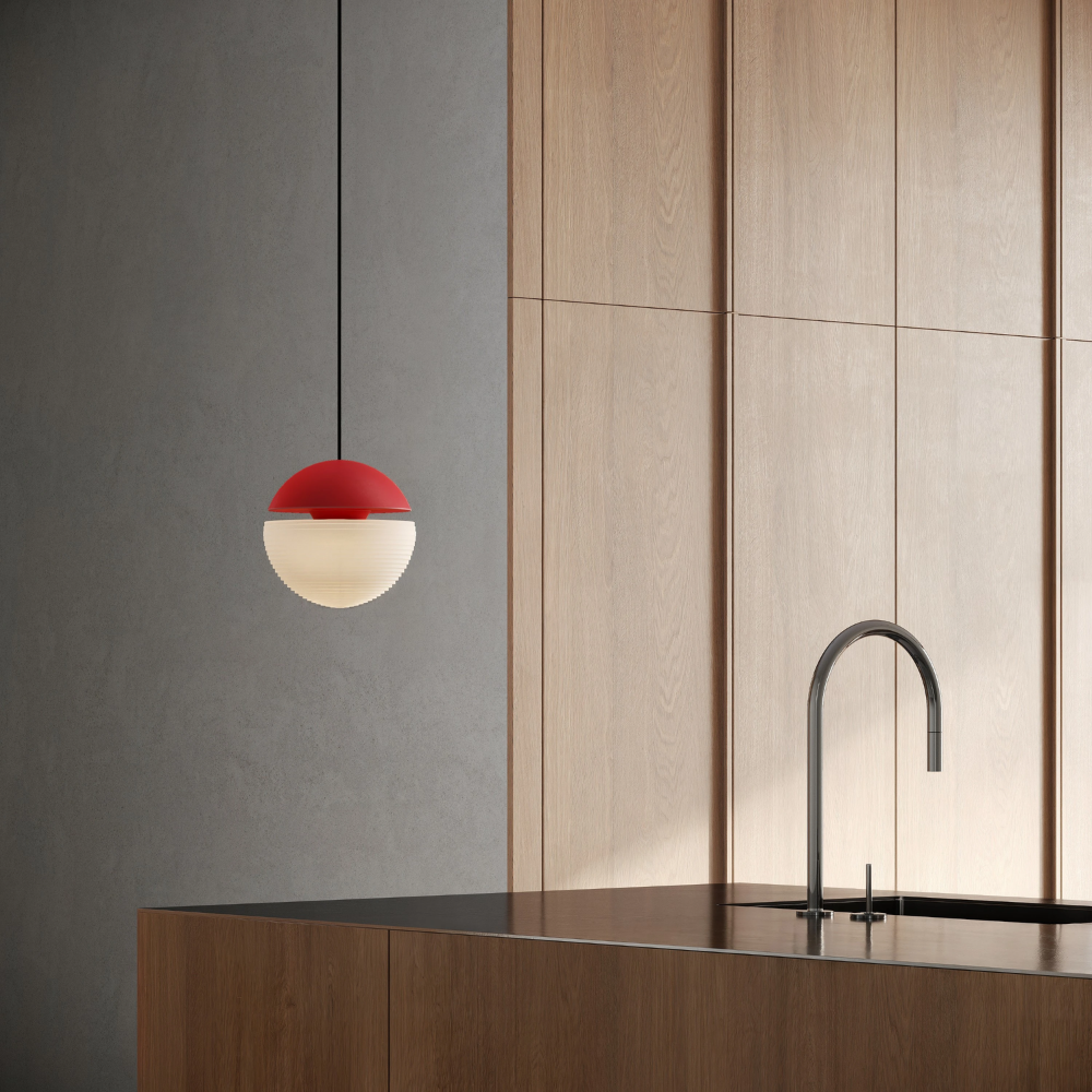 The poppy Cora Pendant Light from Gantri with the black cord in a kitchen and dining area above an island with a sink.