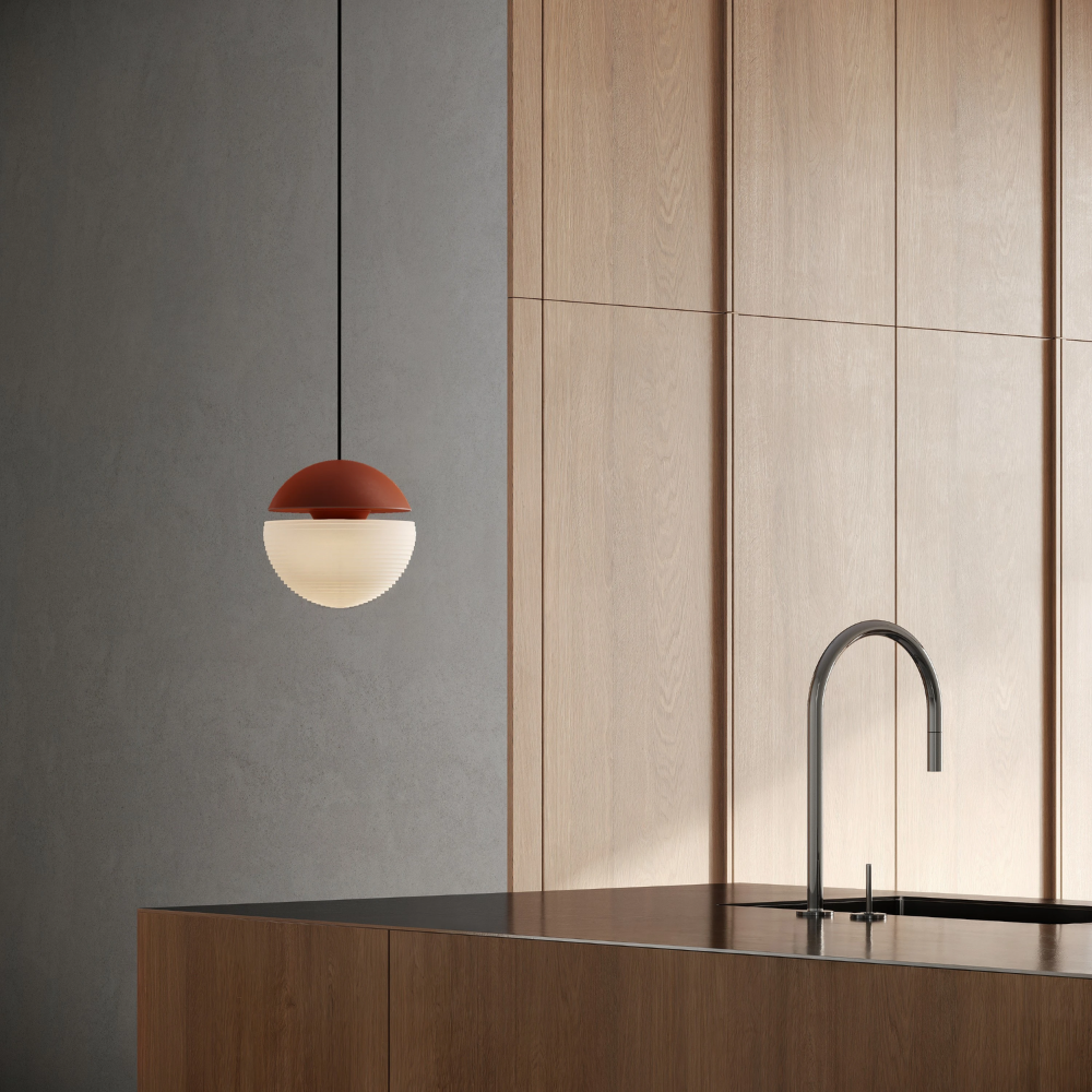 The sedona Cora Pendant Light from Gantri with the black cord in a kitchen and dining area above an island with a sink.