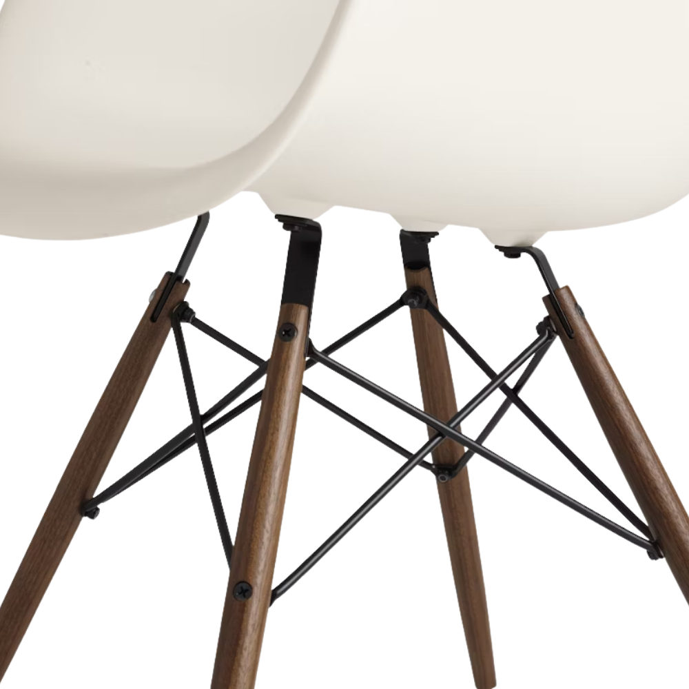 The white shell Eames Molded Plastic Armchair Dowel-Leg Base with the black base and walnut legs close up.