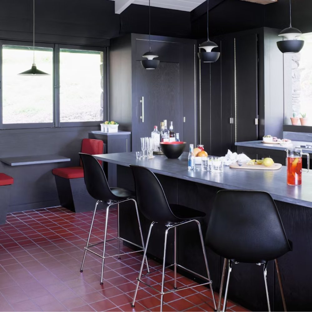 The black shell Eames Molded Plastic Bar Height Stool from Herman Miller in a dining room.