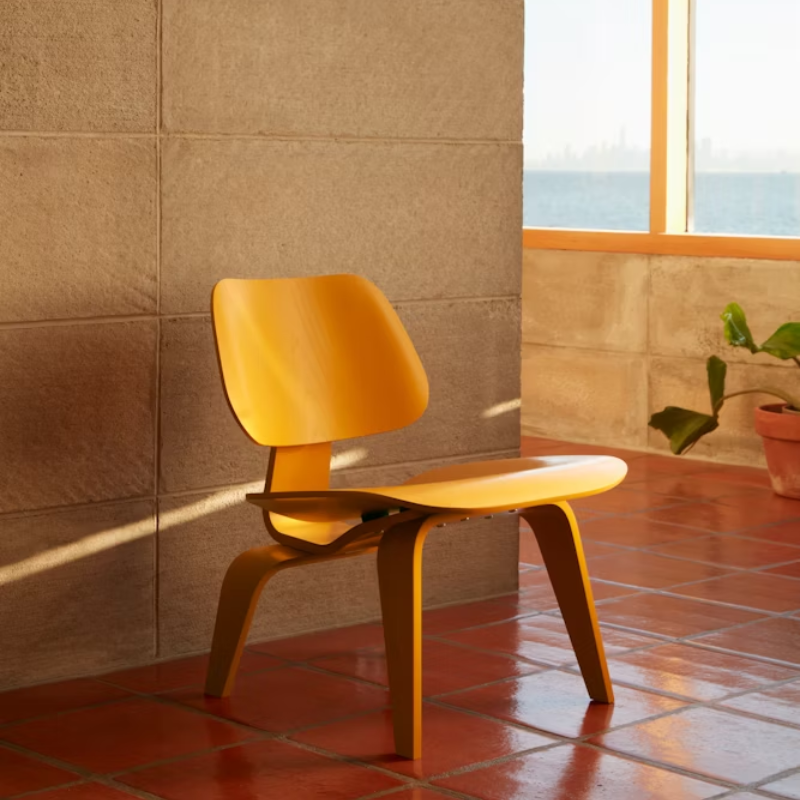 The Deep Yellow Stain Eames Molded Plywood Lounge Chair Wood Base from Herman Miller in a living space.
