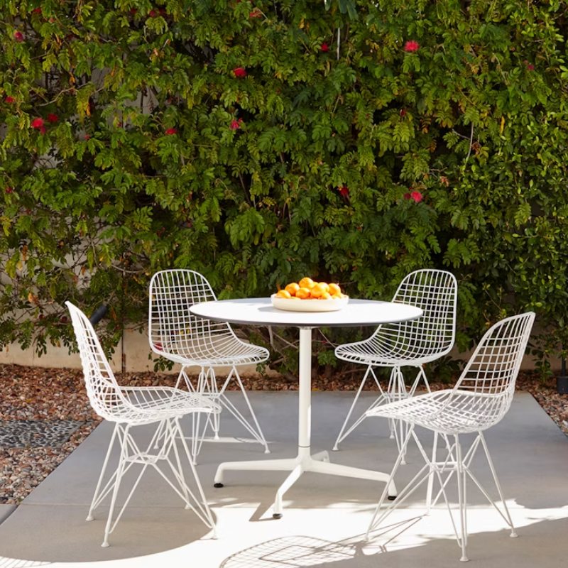 The white Eames Outdoor Wire Chair from Herman Miller in an outdoor dining area.