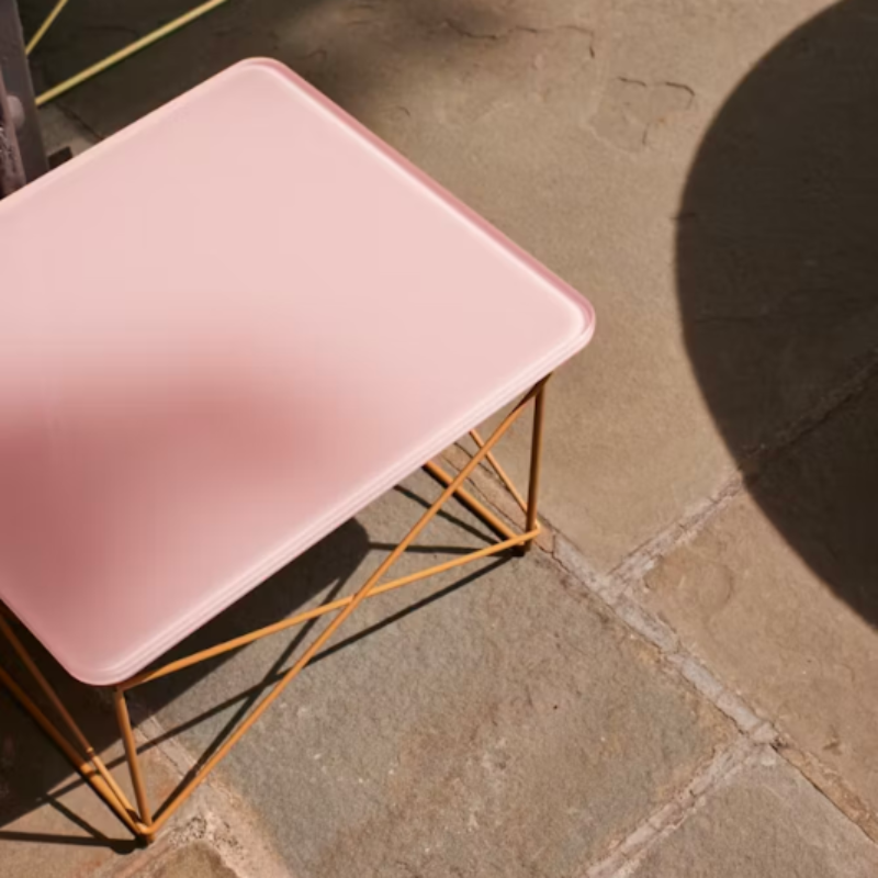 The powder pink and toffee Eames Wire Base Low Table, Herman Miller x HAY from Herman Miller outdoors.