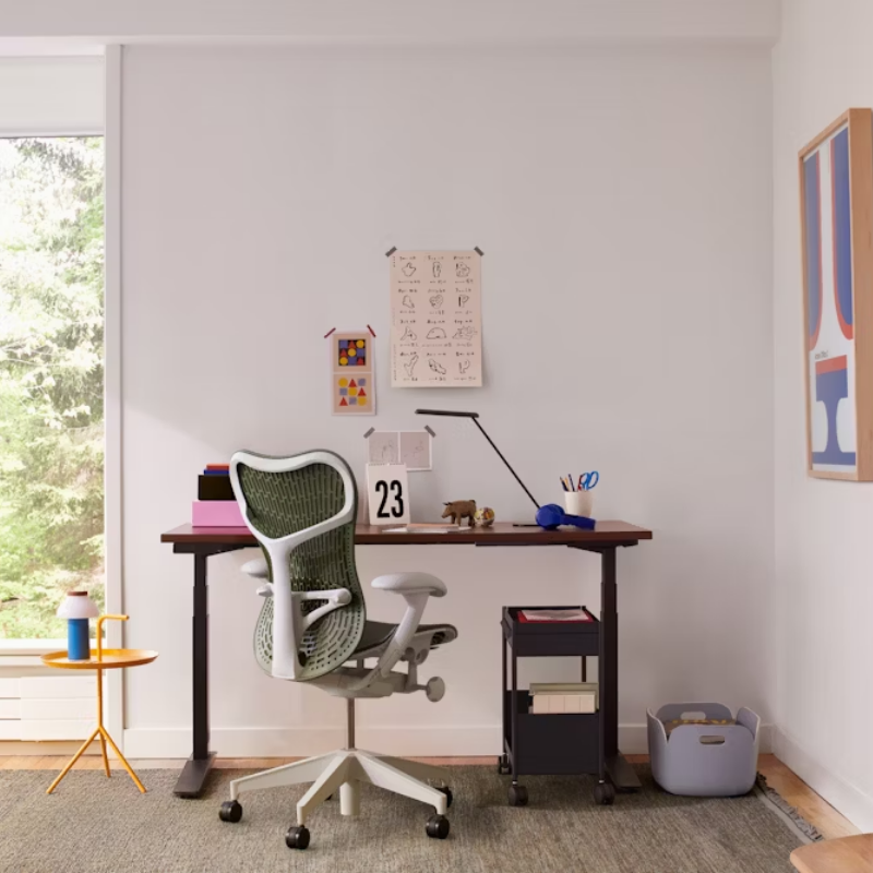 The Mirra 2 Chair from Herman Miller with the butterfly suspension back and alpine frame in olive color in a lounge.