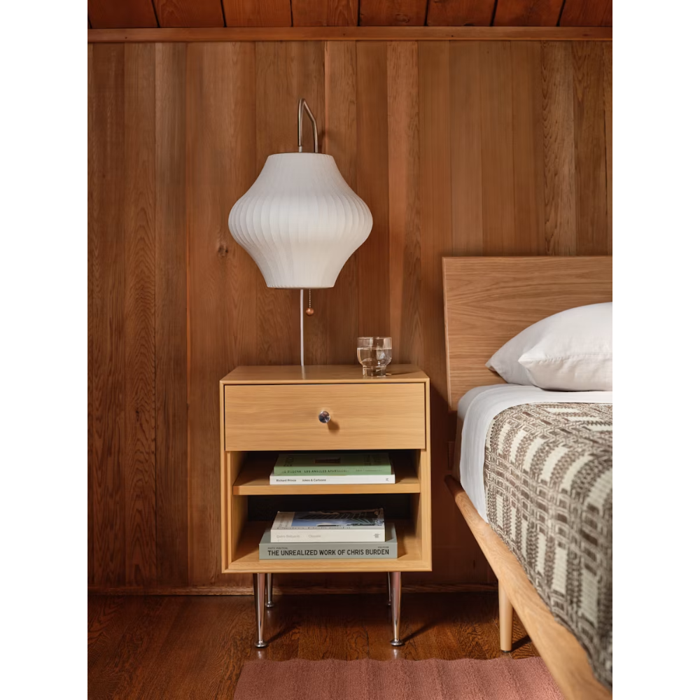The Nelson Pear Wall Sconce from Herman Miller next to a bed.