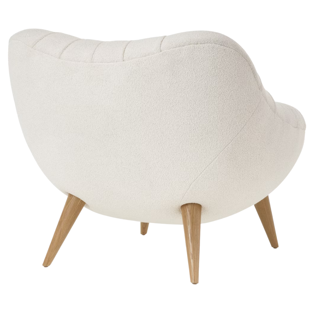 The Rohde Easy Chair from Herman Miller with the warm white whim upholstery and oak leg finish from the back at an angle.