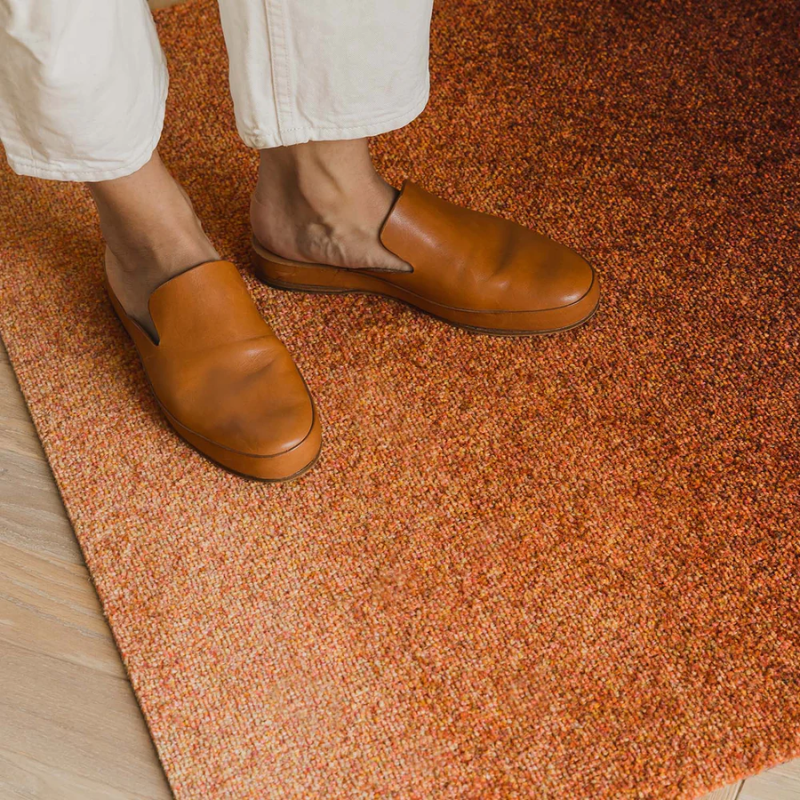 The Dis Doormat from Heymat in rust in a living room.