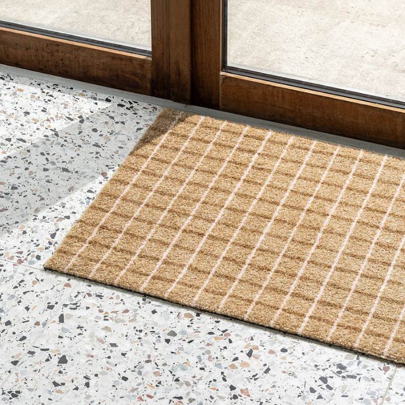 The Grid Doormat from Heymat in chocolate strawberry in an entryway.