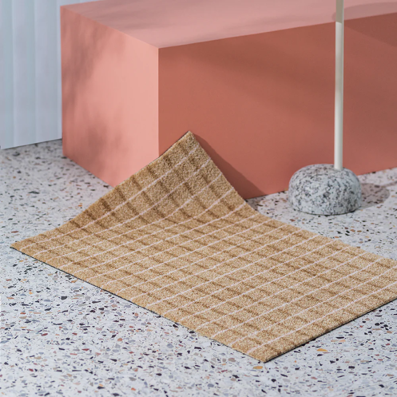 The Grid Doormat from Heymat in chocolate strawberry in a living room.