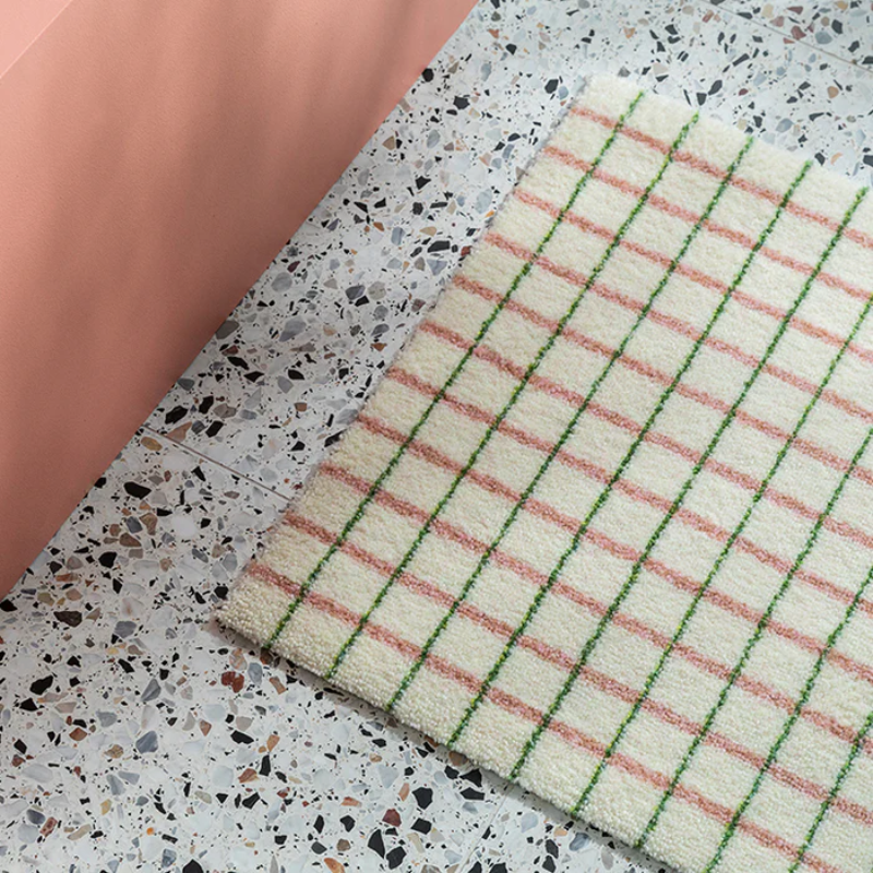 The Grid Doormat from Heymat in lime candycane in a bedroom.
