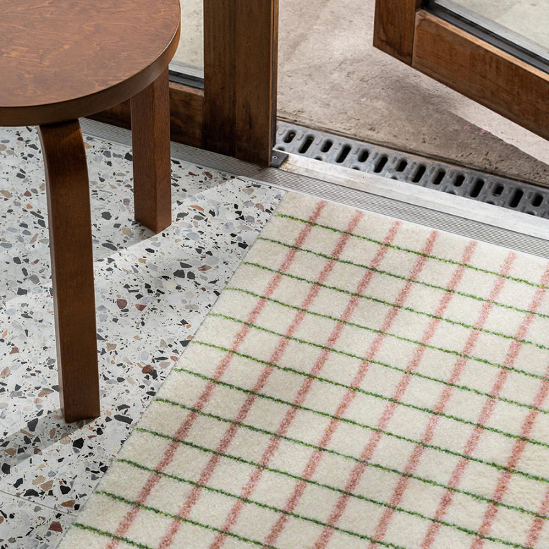 The Grid Doormat from Heymat in lime candycane in a doorway.