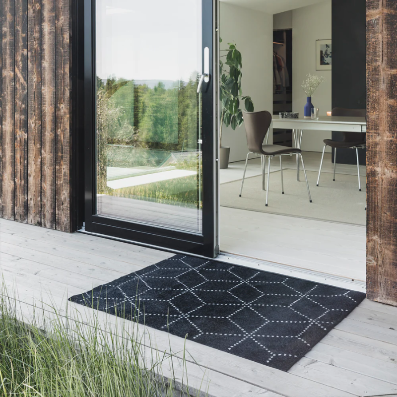 The Hagl Doormat from Heymat in black in a doorway.