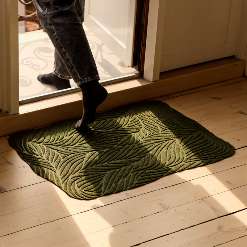 The Twine Doormat from Heymat in green in a doorway.
