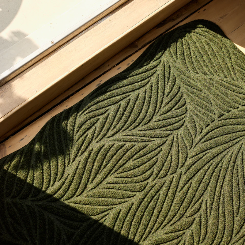 The Twine Doormat from Heymat in green in an entryway.