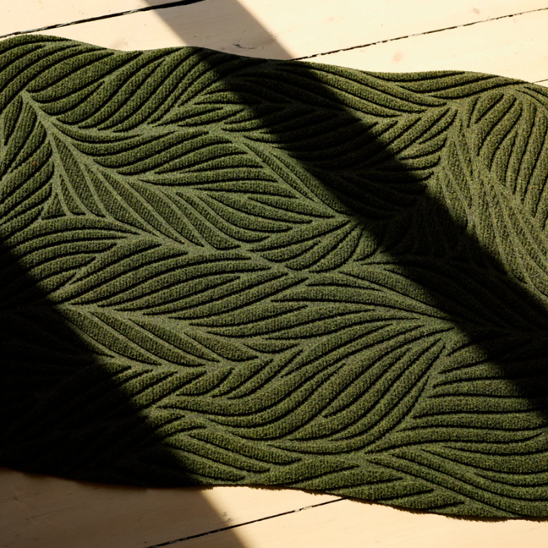 The Twine Doormat from Heymat in green in a living room.