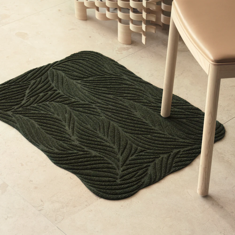 The Twine Doormat from Heymat in green in a lounge.