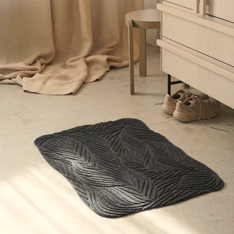 The Twine Doormat from Heymat in grey in a bedroom.