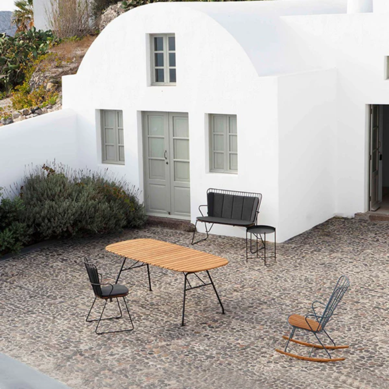 The Edge Outdoor Tray Coffee Table by Houe is in the courtyard with chairs and a table.