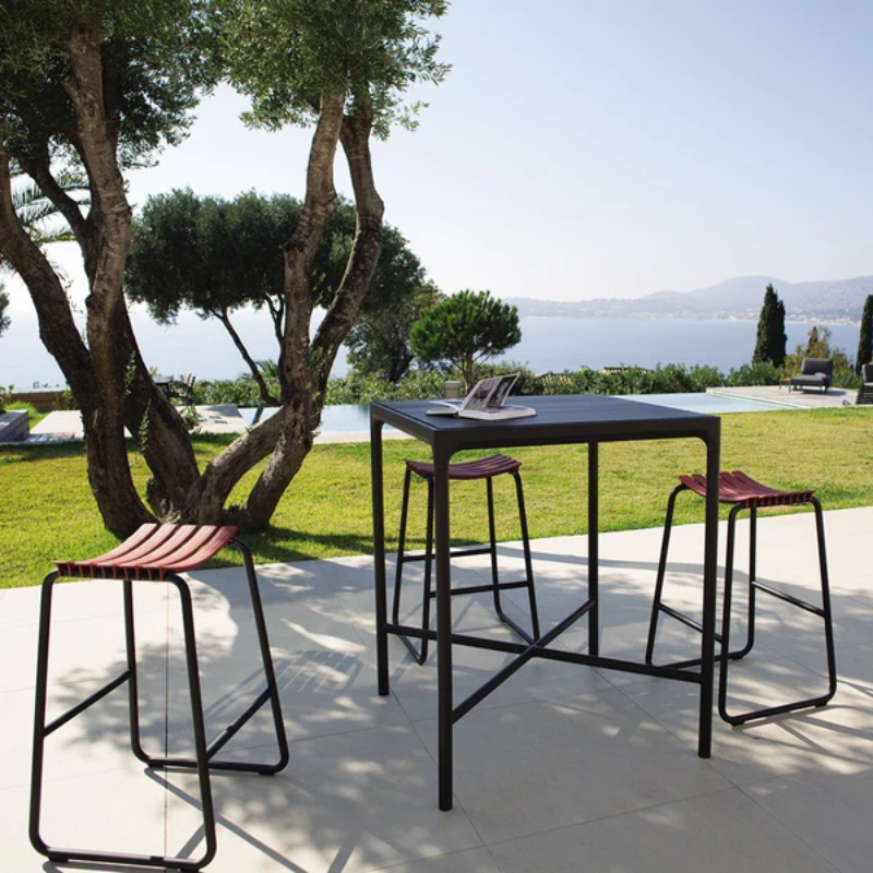 The black Four Outdoor Bar Table Bamboo by Houe with bar chairs in the garden.