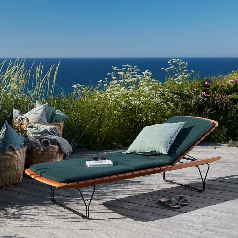 The Molo Sunbed Cushion by Houe with sunbeds on a wooden deck overlooking the ocean.